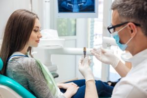 a woman listening as her dentist explains the parts of a dental implant